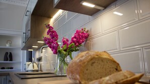 A kitchen with white cabinets, a loaf of bread on a wooden cutting board, and a vase with pink flowers. - Kirk View, 5 minutes from the station and local amenities. (Stirling)