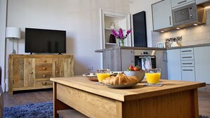 A modern kitchen with a wooden island, a flat-screen TV, and a microwave. - Kirk View, 5 minutes from the station and local amenities. (Stirling)
