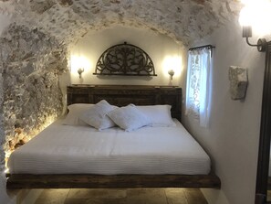 A bedroom with a stone wall, wooden headboard, and two bedside lamps.
