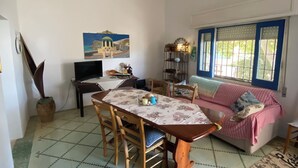 Un coin repas avec une table dressée pour quatre personnes, un canapé et un tableau accroché au mur.