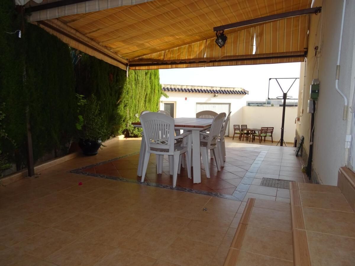 An outdoor patio with a covered seating area, a potted plant, and a tiled floor.