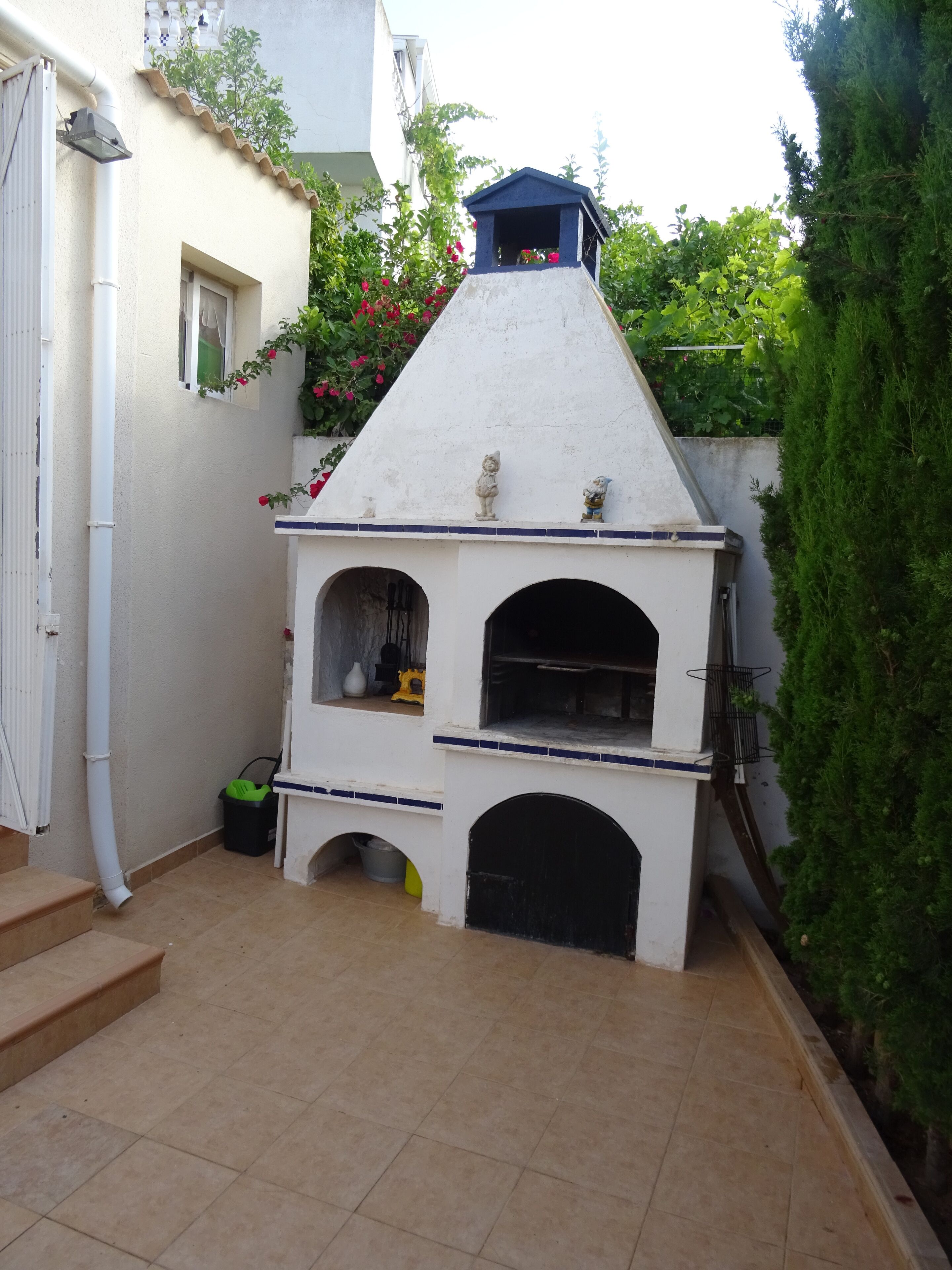 A small outdoor kitchen area with a white oven, a window, and a door.