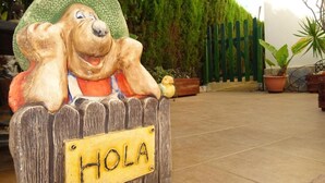 Una valla de madera con un letrero que dice 'HOLA' y una estatua de perro caricaturesco.