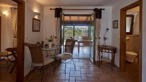 Une pi èce comprenant un coin repas, une table avec des chaises, une petite table avec un vase et une vue sur l’extérieur.