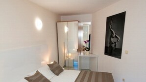 Ein Hotelzimmer mit einem großen Bett, Nachttischen, einem Spiegel und einem gerahmten Bild an der Wand.