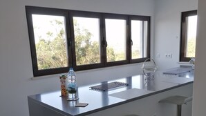 A modern kitchen with a central island, bar stools, and large windows. - Ribamar-Quinta Mar and Terra Villas (Ribamar)