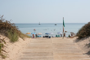 A wooden boardwalk leading to a beach with umbrellas and beach chairs. - OLIVA HOLIDAYS 1- BY THE SEA WITH SWIMMING POOL (Oliva)