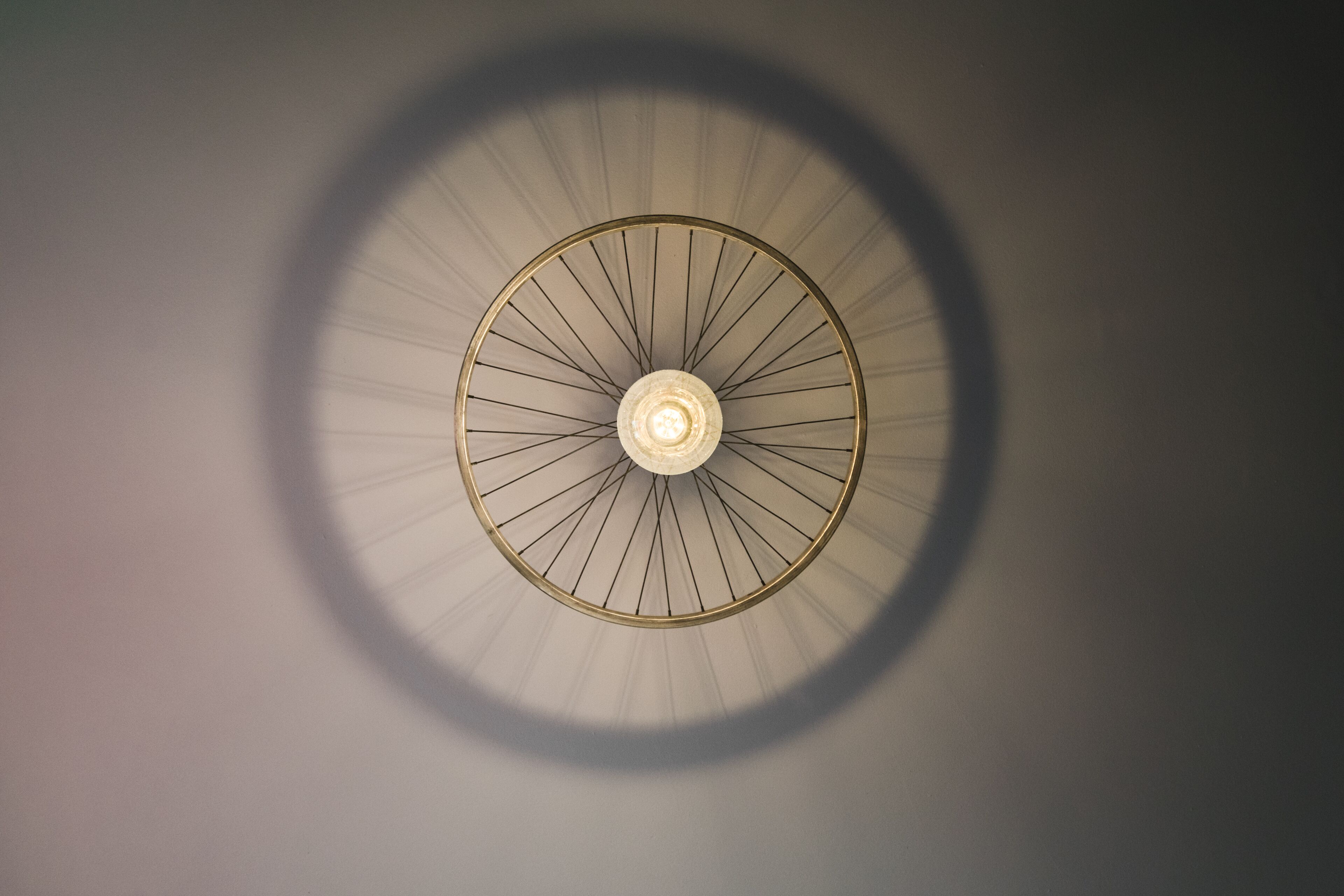Luminária de teto circular com lâmpada central e braços irradiando.