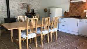 Un coin repas avec une table et des chaises en bois, un réfrigérateur blanc et un sol carrelé.