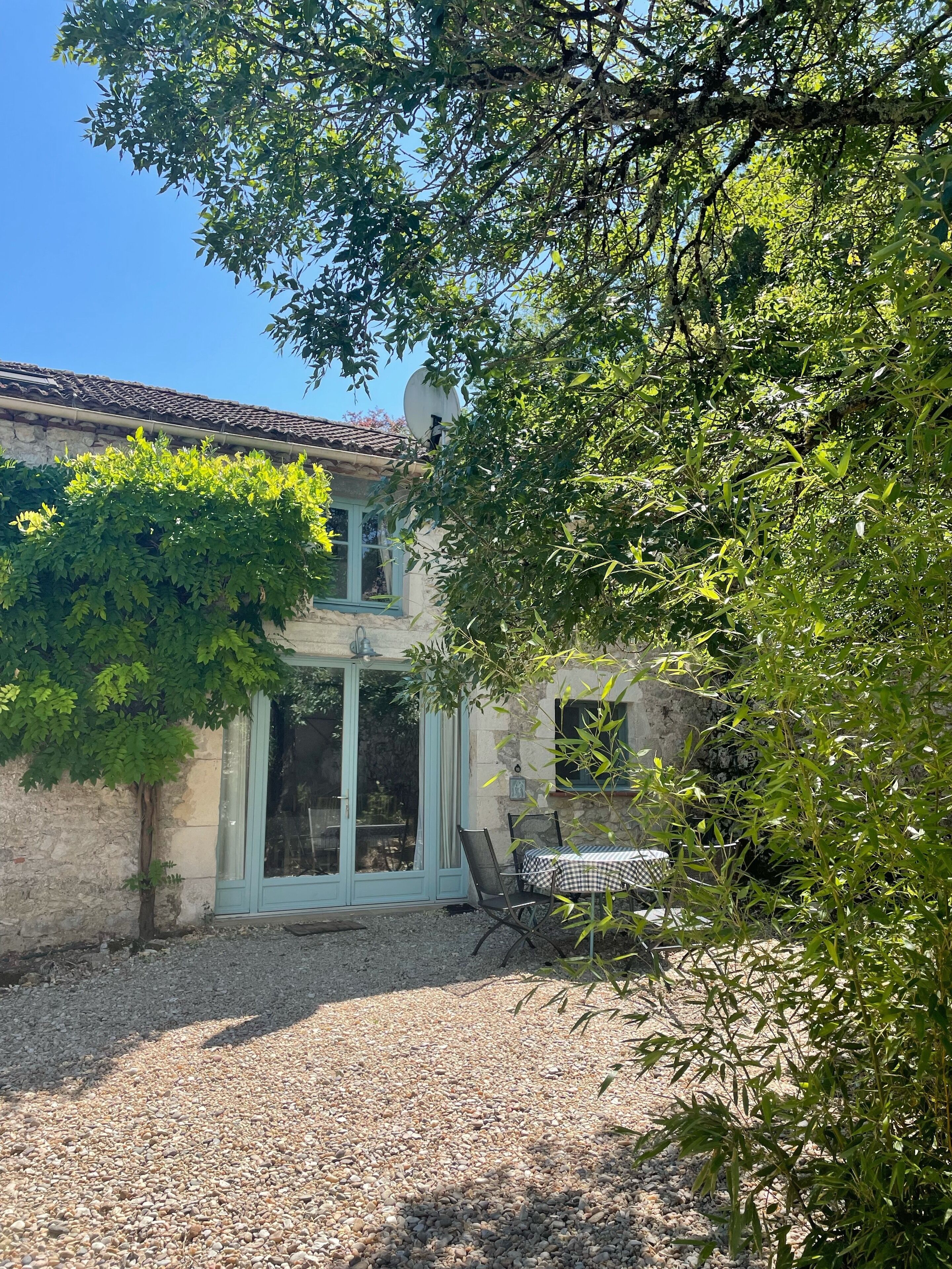 A rustic building with a tiled roof, a glass door entrance, and a gravel patio area.