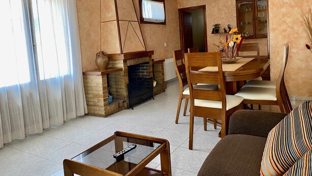 Uma sala de estar com lareira, mesa de jantar e cadeiras.