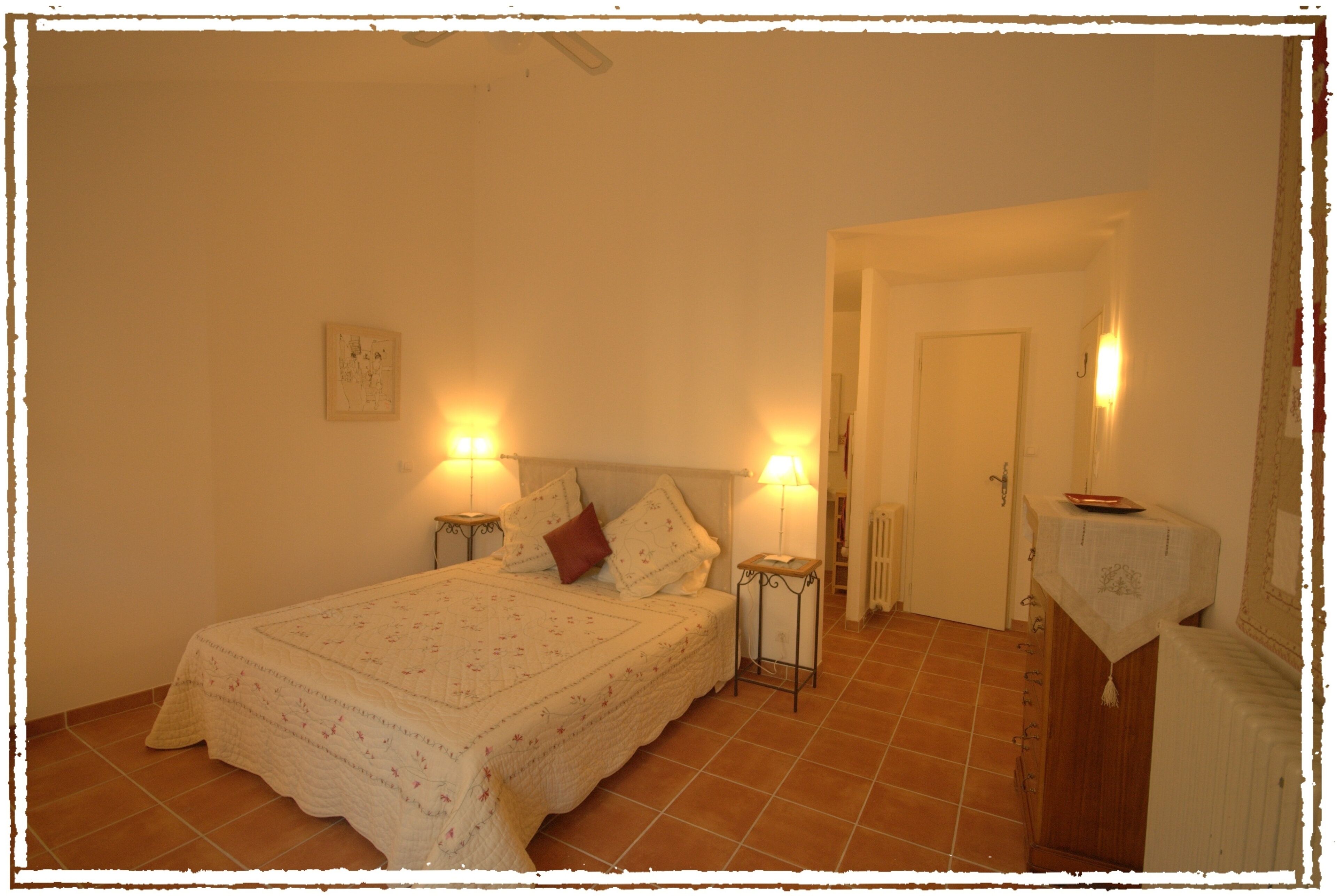 Une chambre à coucher avec un lit, deux lampes de chevet, une table de chevet, une porte et un radiateur.