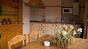 Et køkken med træskabe, en mikrobølgeovn og et spisebord med stole.