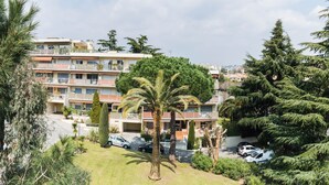 A multi-story residential building with balconies, surrounded by lush greenery and parked cars. - enjoy this apartment located 10 minutes from the beaches (Cannes)