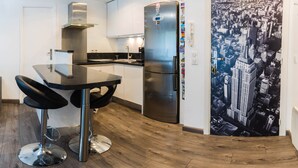 A modern kitchen with a stainless steel refrigerator, a black countertop, and two bar stools. - enjoy this apartment located 10 minutes from the beaches (Cannes)
