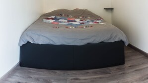 A small, dark-colored bed with a quilted blanket featuring a map of the United States. There are three wall-mounted light fixtures above the bed. - enjoy this apartment located 10 minutes from the beaches (Cannes)