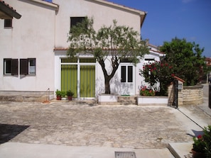 Traditional Mediterranean-style building with a charming courtyard featuring a green door and potted plants.