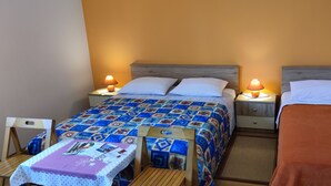 Una habitación de hotel con dos camas individuales, una mesita pequeña con mantel morado y dos mesitas de noche con lámparas.