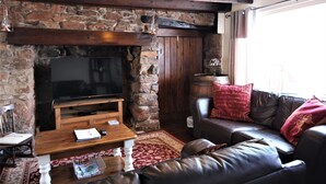 A cozy living room with a stone fireplace, a leather sofa, and a wooden coffee table. - Gorgeous Waterside Fisherman's Cottage, Free Parking, Harbour Views, Disney+ (Brixham)