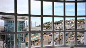A view through a window with a grid pattern, displaying a town with buildings, a road, and a construction site. - Gorgeous Waterside Fisherman's Cottage, Free Parking, Harbour Views, Disney+ (Brixham)