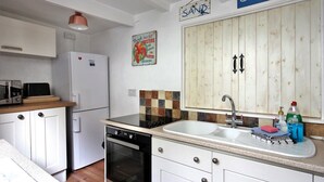 A kitchen with white cabinets, a refrigerator, a dishwasher, and a sink. There are decorative signs on the wall and a microwave on the counter. - Gorgeous Waterside Fisherman's Cottage, Free Parking, Harbour Views, Disney+ (Brixham)