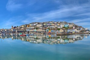 A coastal town with colorful buildings, a calm harbor, and a clear blue sky.