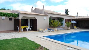 Zona de piscina con alberca, sillas de descanso y una mesa con sillas.