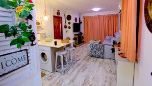 Ett kompakt bostadsutrymme med ett köksområde, en soffa och ett matbord.