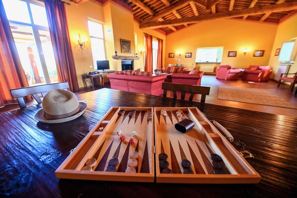 A mahjong table in a warmly lit room with wooden floors, red sofas, and a fireplace.
