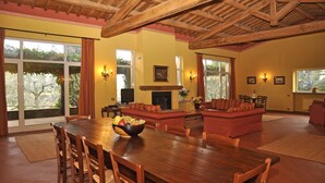 A spacious living room with a wooden dining table, red sofas, and a fireplace.