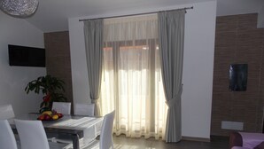 A modern dining area with a glass table, white chairs, and a fruit bowl. - Apartment "Full Moon" (Tusa)