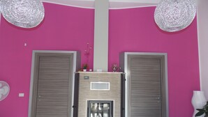 A room with pink walls, two doors, a water dispenser, and a table with chairs. - Apartment "Full Moon" (Tusa)