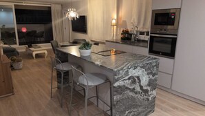 A modern kitchen with a marble island, bar stools, and built-in appliances. - COZY AND SUNNY PENTHOUSE IN THE HEART OF THE CITY (Alicante)