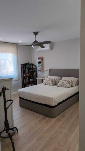 A bedroom with a bed, a desk, a chair, a bookshelf, and a ceiling fan.