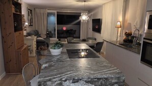 A modern kitchen with a marble countertop, a dining area with a table and chairs, and a living room with a sofa and a chandelier. - COZY AND SUNNY PENTHOUSE IN THE HEART OF THE CITY (Alicante)