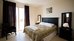 A hotel room with a bed, a chair, a desk, a mirror, and a painting on the wall. - Villa Chrisanthi 300m from Coast Free (Coral Bay)