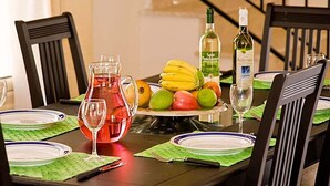 A dining table set with plates, a pitcher, a bottle, and a bowl of fruit. - Villa Chrisanthi 300m from Coast Free (Coral Bay)