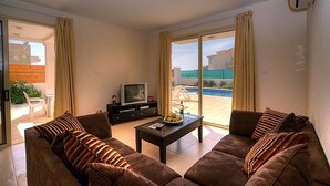 A living room with a sofa set, a coffee table, and a television. - Villa Chrisanthi 300m from Coast Free (Coral Bay)