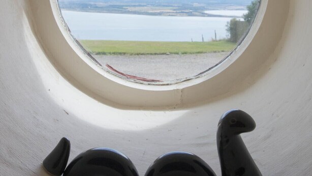 A round window with a view of a lake and distant landscape. - Stunning quiet location with views across the Moray Firth home to dolphins. (Rosemarkie)