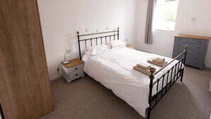 A bedroom with a bed, nightstand, dresser, and window with curtains. - Stunning quiet location with views across the Moray Firth home to dolphins. (Rosemarkie)
