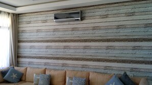 Ein Wohnzimmer mit Holzwand, einem Flachbildfernseher über einem beigen Sofa mit gemusterten Kissen.