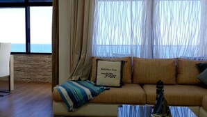 Ein Wohnzimmer mit einer Couch, einer Lampe und Meerblick.
