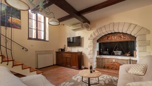 Ein Wohnzimmer mit Kamin aus Stein, einem an der Wand befestigten Fernseher und einer Treppe mit Holzboden.