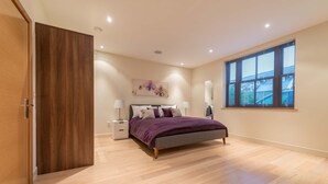 Un dormitorio con cama, mesitas de noche, una ventana y un cuadro en la pared.