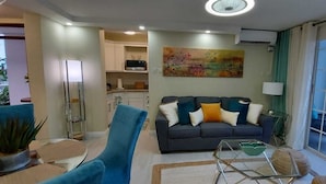 Una sala de estar con un sofá, una mesa de centro de vidrio y vistas al exterior a través de un ventanal.