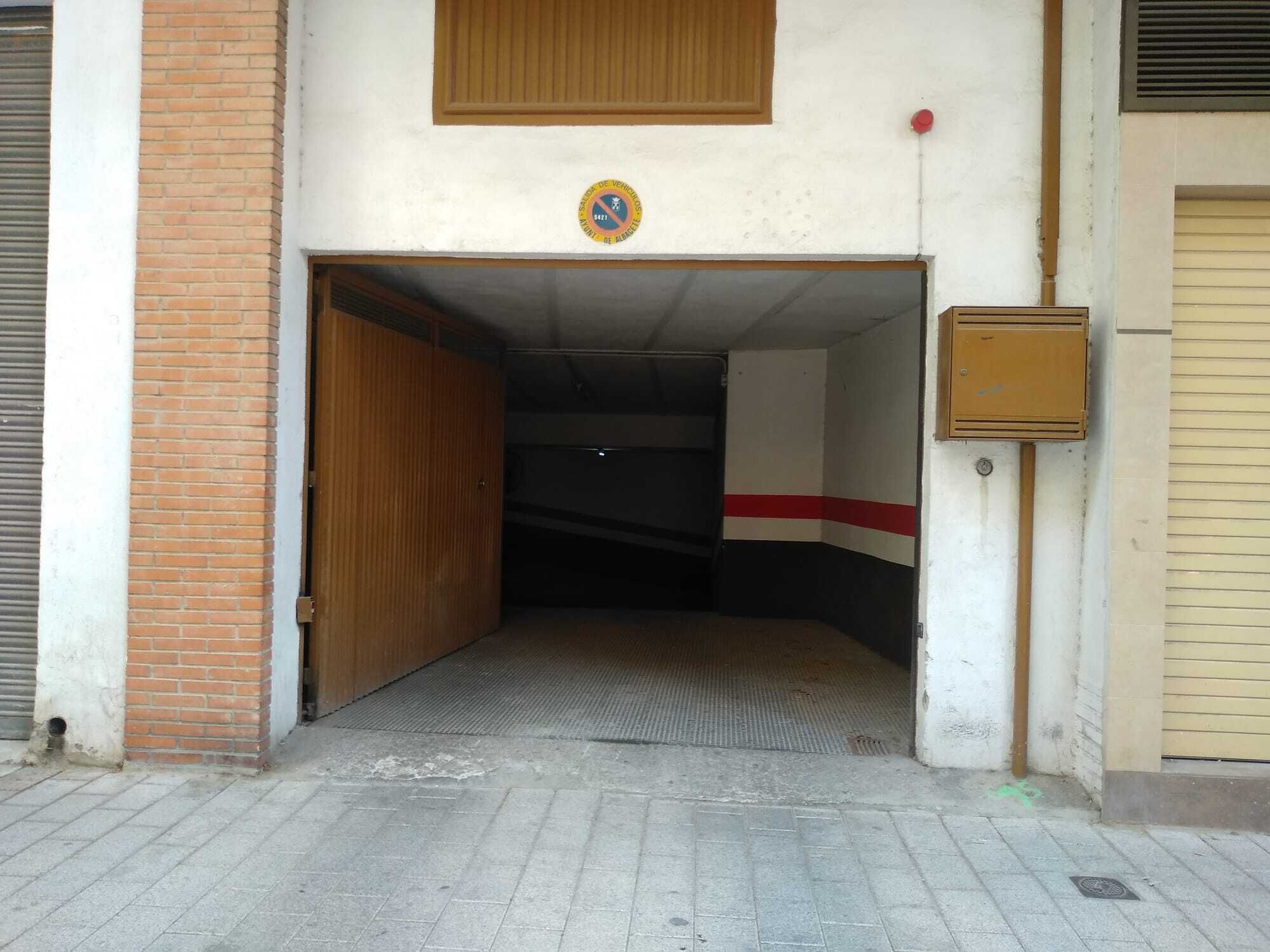 Een ingang van een gebouw met een houten deur, een muur met rode en witte strepen en een klein bord boven de deur.