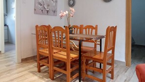 A dining area with a wooden table and chairs, a floral painting on the wall, and two decorative plates. - Apartment very central and very well connected. (Albacete)