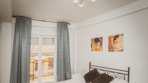 A bedroom with a bed, grey curtains, a tiled floor, and two artworks on the wall. - Apartment very central and very well connected. (Albacete)