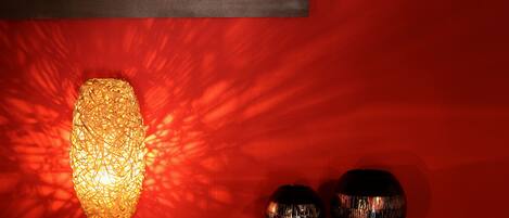 A table with a lamp and two vases against a red wall.