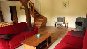 Een woonkamer met een rode bank, een houten salontafel, een televisie en een open haard.